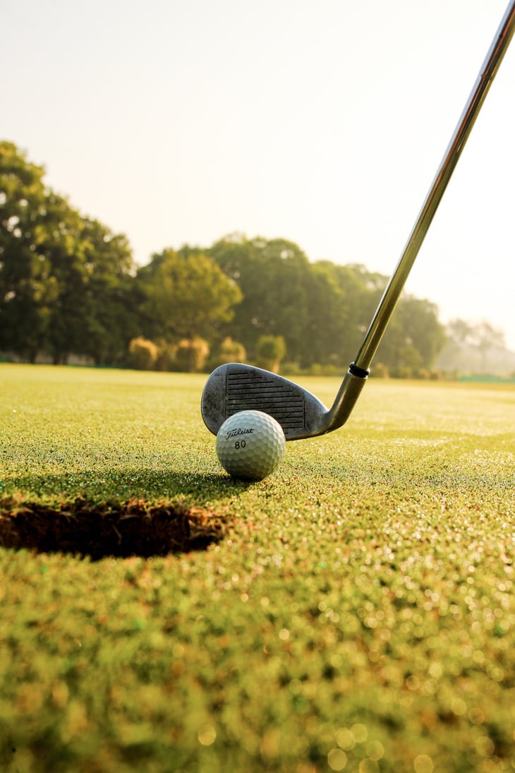 Golf club hitting ball on field